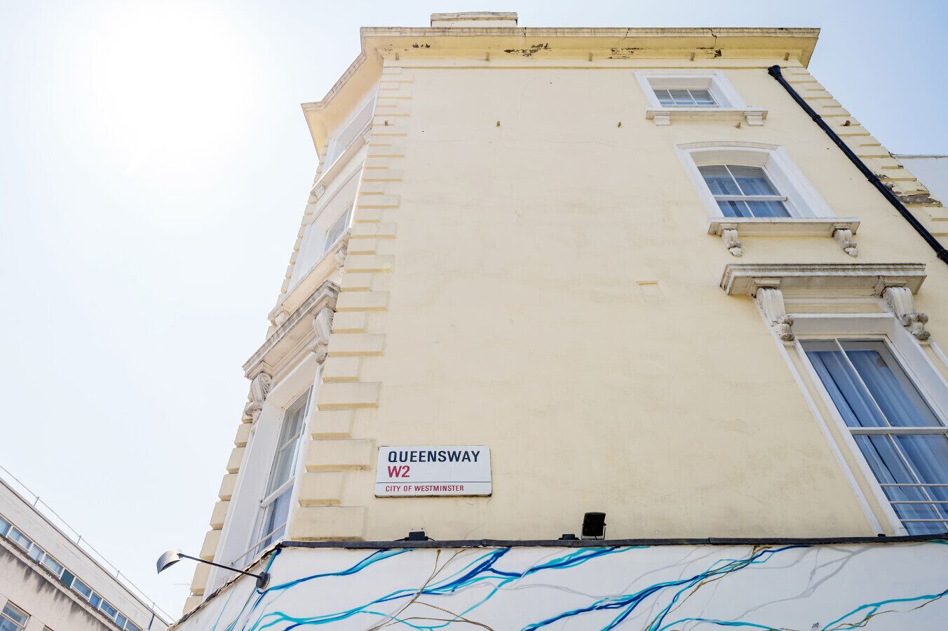 A building with a sign reading "Queensway W2 City of Westminster."