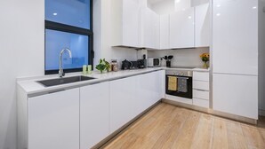 A modern kitchen with white cabinets, a stainless steel sink, a microwave, and a stove.
