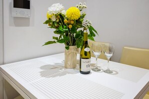 Une table avec une bouteille de vin, deux verres et un vase de fleurs.