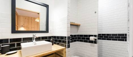 A bathroom with a white sink, mirror, and black and white tiled walls.