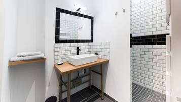 A modern bathroom with a white sink, black and white tiled walls, and a wooden countertop.