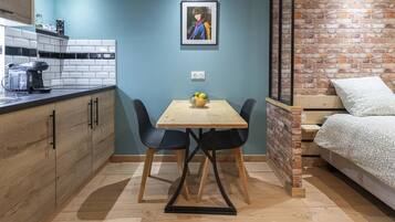 Una cocina compacta con cafetera, una mesa de comedor y dos sillas, y una pared de ladrillo.