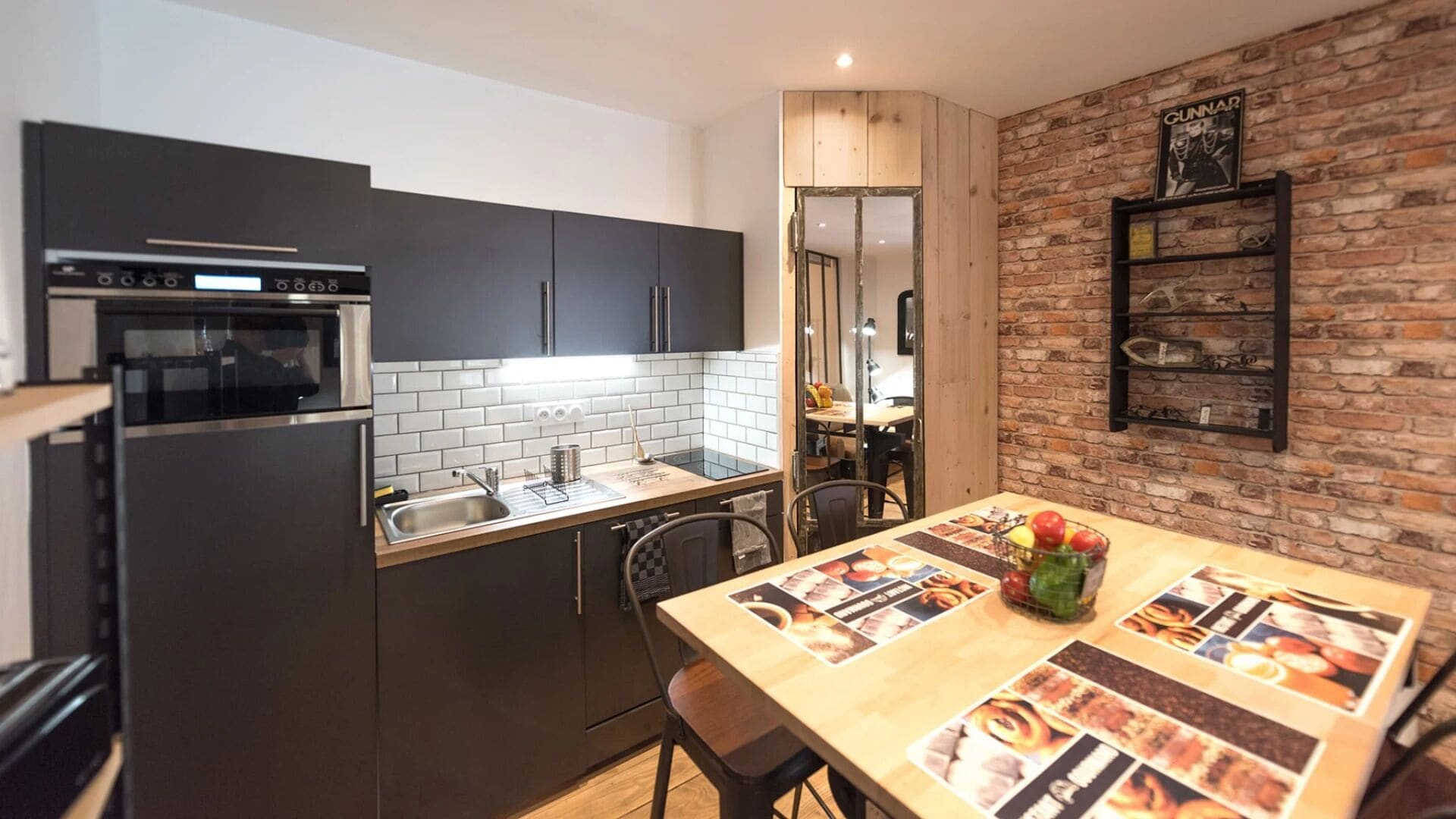 Een moderne keuken met donkere kastjes, een roestvrijstalen oven en een betegelde achterwand.
