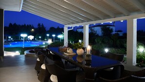 An outdoor patio with a pool, dining table, and chairs. - Escape Villa in Melissochori (Oraiokastro)
