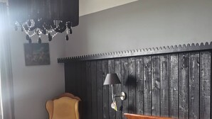 Et soveværelse med seng, stol, lampe og træsenggavl.
