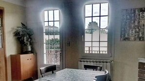 Et spiseområde med et bord, stole, en potteplante og et vindue med udsigt.