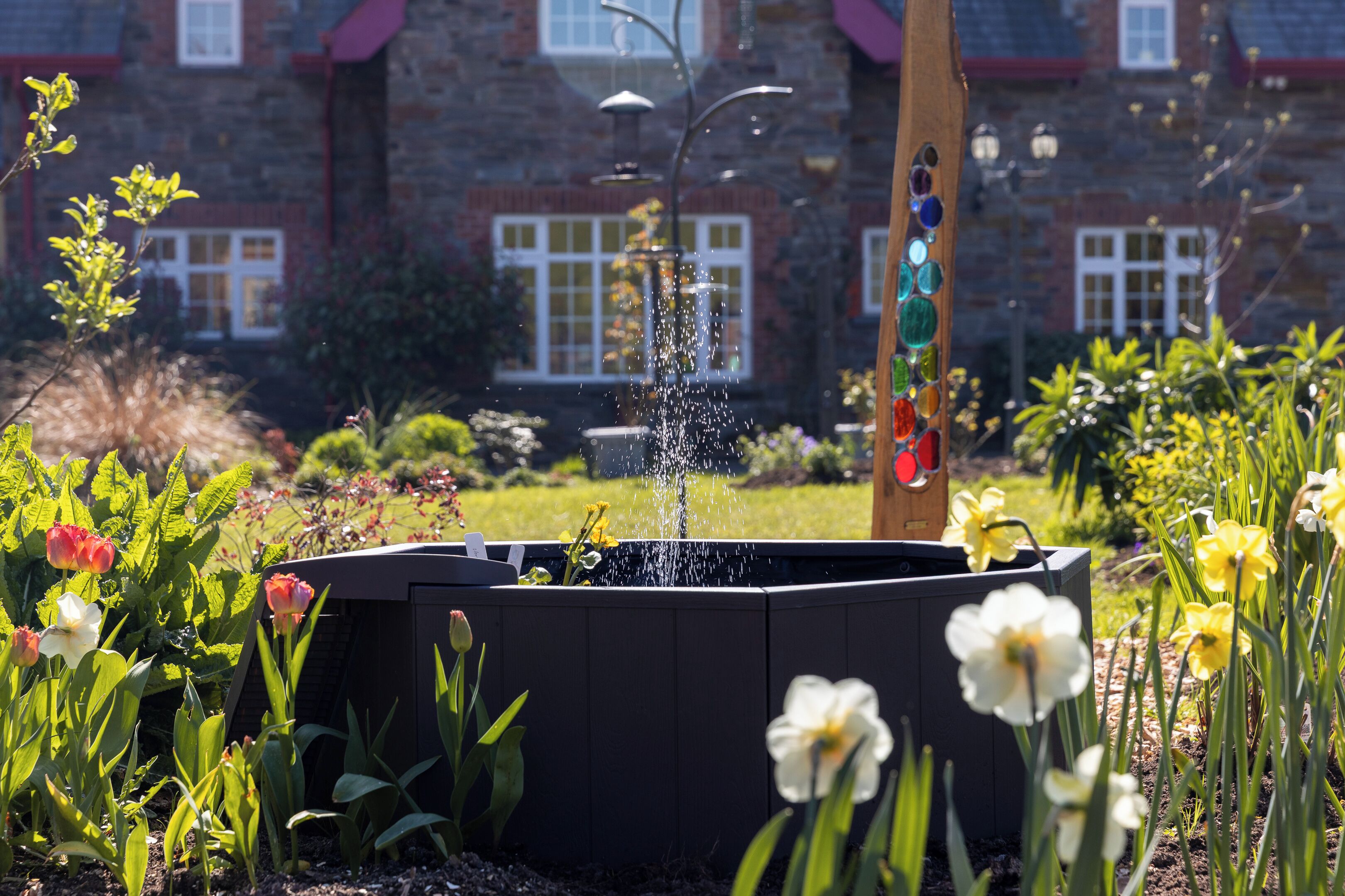 Een tuin met een waterpartij en bloemen.