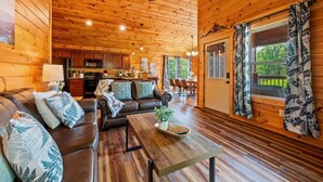 Interno di una baita in legno con soggiorno, cucina e zona pranzo.