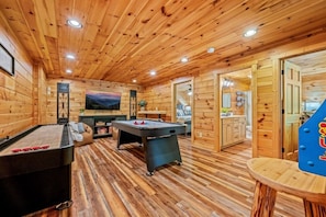 Un interior de madera con mesa de billar, mesa de futbolín y televisor.