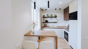 Une cuisine moderne avec des armoires blanches, un comptoir en bois et un four encastré. Une fenêtre offre une vue sur l’extérieur, et un vase rempli de fleurs est posé sur le comptoir.