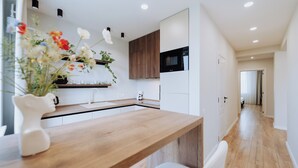 Une cuisine moderne avec des plans de travail en bois, des armoires blanches et un micro-ondes encastré.