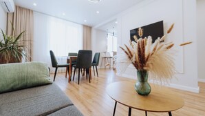 Un salon moderne avec un canapé, une table à manger et un vase décoré de plumes d’herbe des pampas.