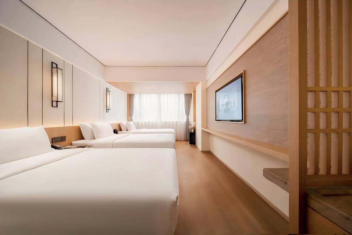 Ein Hotelzimmer mit zwei Betten, einem Fernseher und einer Wandpaneele aus Holz.
