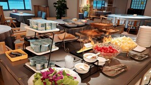 Montaje de bufé con diversos alimentos, como ensaladas, frutas y bebidas.
