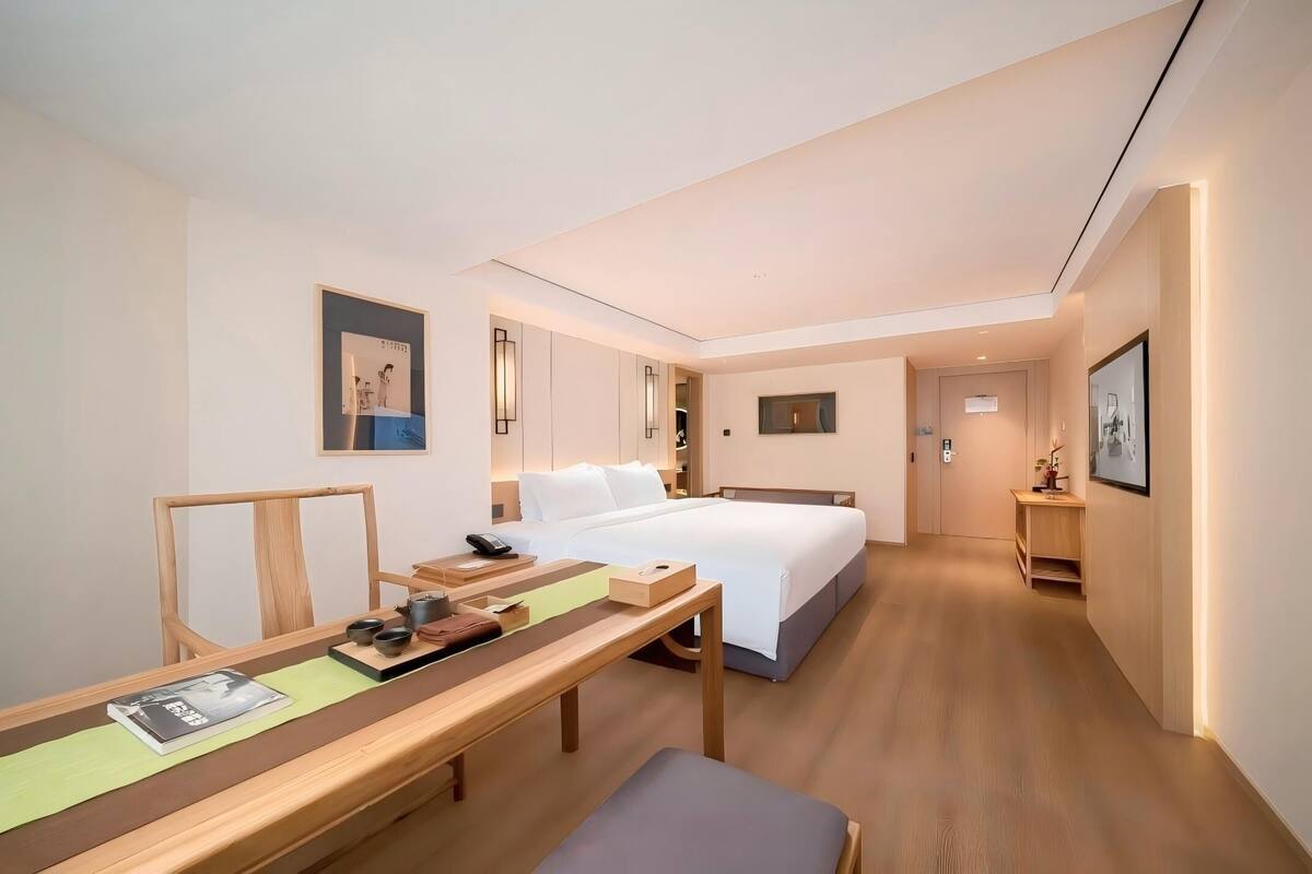 Ein Hotelzimmer mit Bett, Nachttisch und Schreibtisch mit Stuhl.