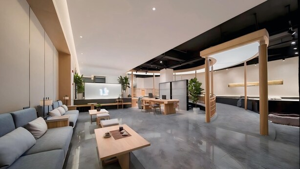 Un espacio de oficina moderno con una pantalla grande, zonas de estar y un mostrador de recepción de madera.