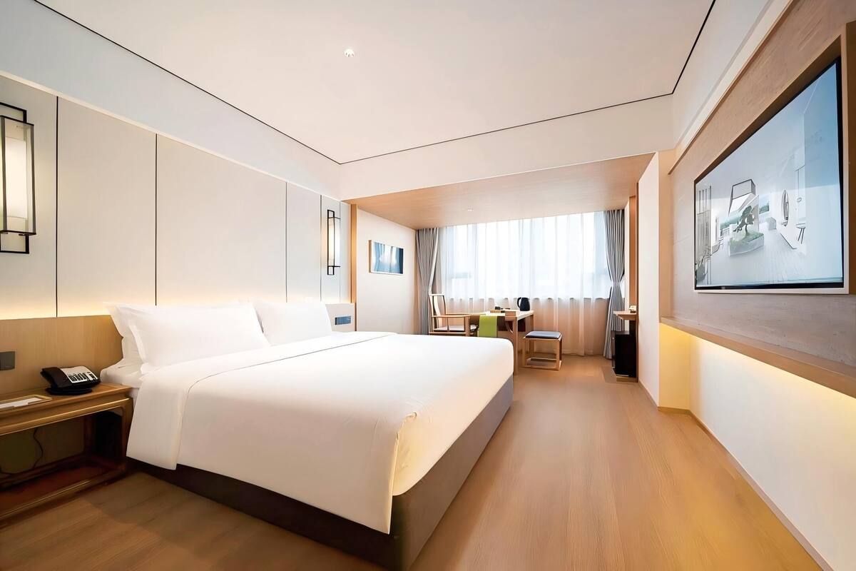 Ein modernes Hotelzimmer mit einem großen Bett, einem Nachttisch und einem Schreibtisch mit Stuhl.