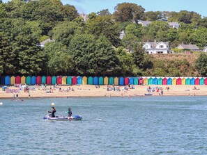 A beach with colorful beach huts and a row of houses in the background. - 3 Glyn Y Mor (Pwllheli)