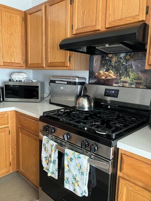 Une cuisine équipée de meubles en bois, d’un four à micro-ondes, d’un grille-pain, d’une bouilloire et d’une cuisinière.