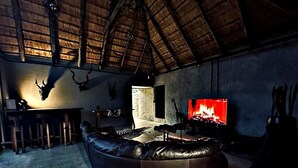 Ein rustikales Interieur mit einem Ledersofa, einem Fernseher, der ein Feuer zeigt, und Geweihen an der Wand.
