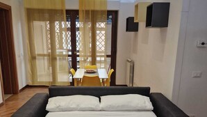 A bedroom with a bed, a small table, and chairs in the background. - Cozy and Comfortable Apartment near Fiumicino Airport (Lazio)