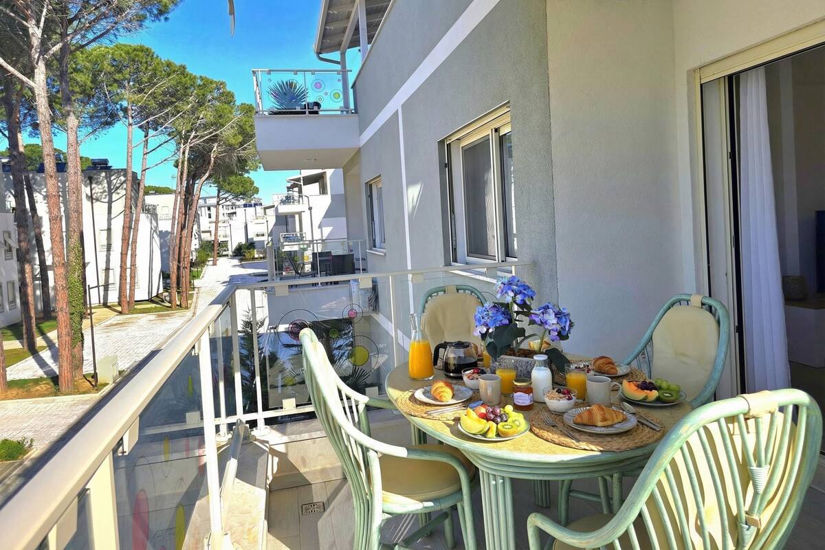 A balcony with a table set for breakfast, including fruits, pastries, and beverages.