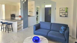 Un salon moderne avec un canapé bleu, une table basse en marbre et un lustre.