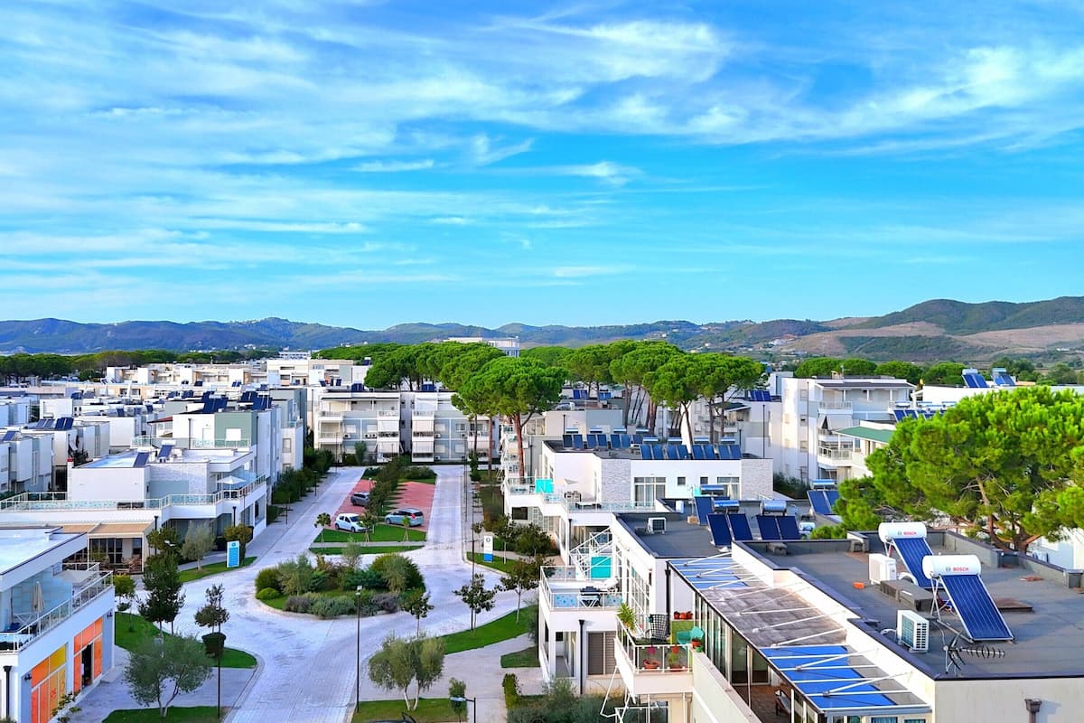A modern residential area with multiple buildings, solar panels on rooftops, and a clear sky.