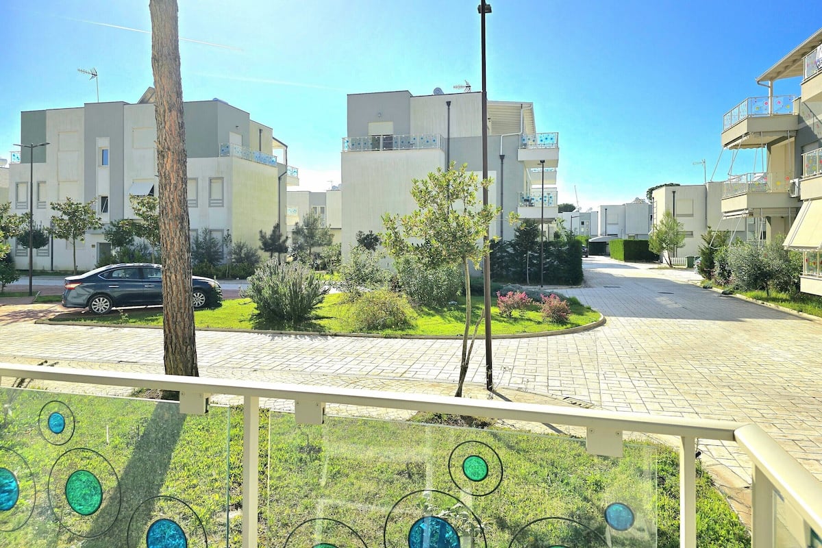 A residential area with modern apartment buildings, a paved driveway, and a small garden area.