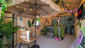 A cozy indoor space with a thatched ceiling, a wicker chair, and a staircase leading to a higher level.