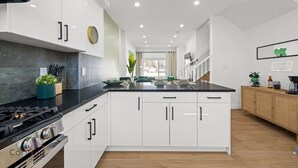 A modern kitchen with white cabinets, a black countertop, and a built-in stove.