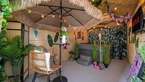 A cozy indoor space with a thatched ceiling, a wicker chair, and a staircase leading to a higher level. - Pretty in Pink | Hot Tub | 10 min to WEM | KingBed (Edmonton)