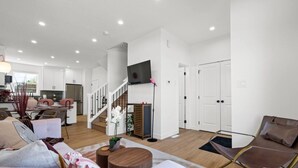 A spacious living area with a staircase, a dining area, and a kitchen. - Pretty in Pink | Hot Tub | 10 min to WEM | KingBed (Edmonton)