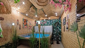 Een wellnessruimte met een jacuzzi, bamboe wanden en tropische planten.