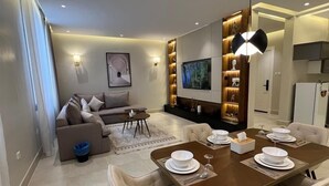 Un salon moderne comprenant un coin repas, un canapé, un téléviseur et une bibliothèque.