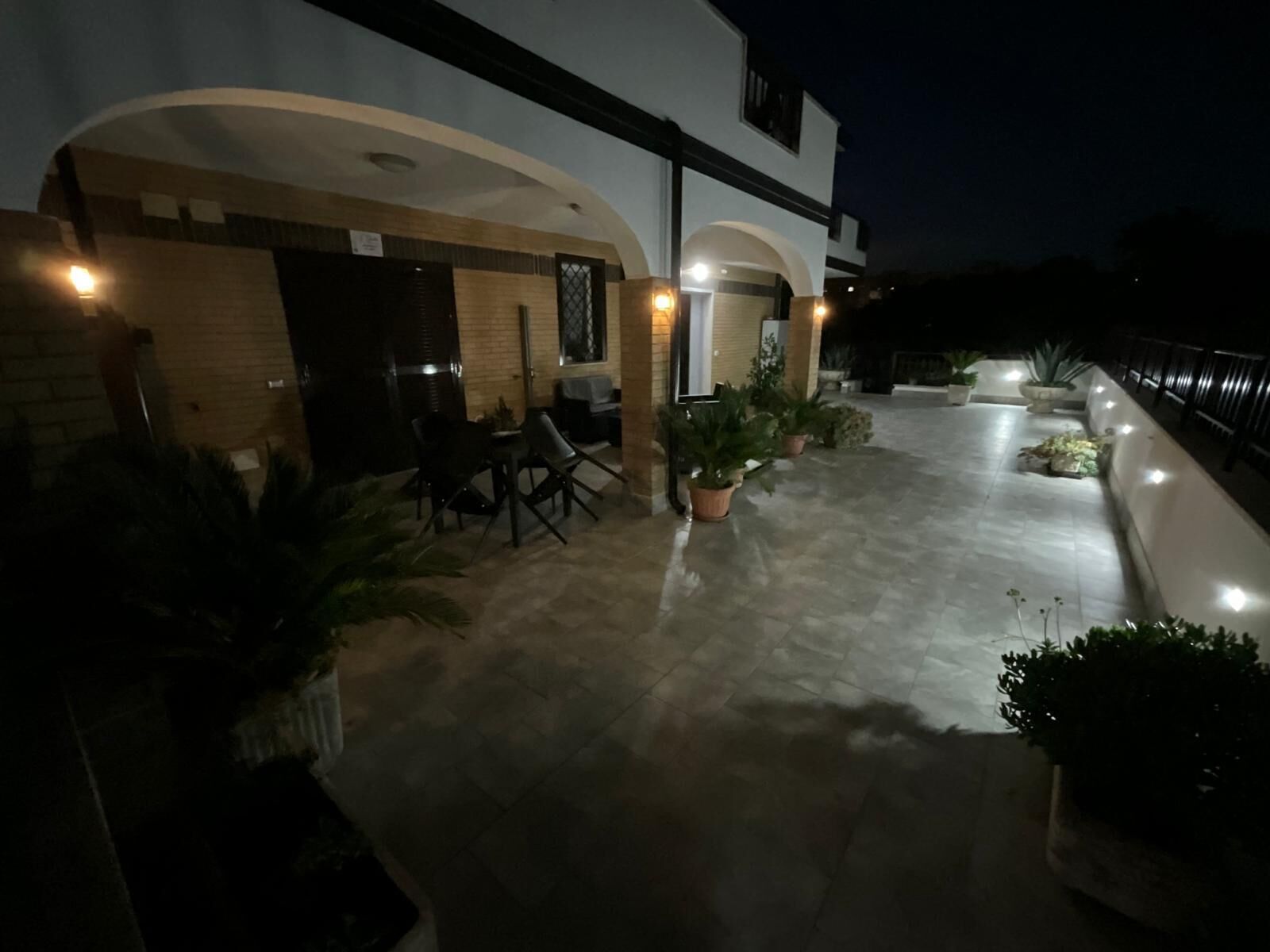 Ein gut beleuchteter Außenbereich mit Terrasse, Sitzgelegenheit und Topfpflanzen.