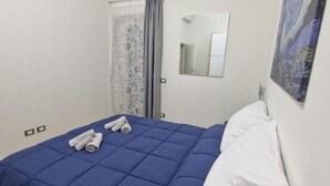 A hotel room with a bed, a mirror, and a painting on the wall. - Greta family house: Luke (Roma)