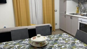 A compact kitchen with white cabinets, a sink, and a dining area with a table set for two. - Greta family house: Luke (Roma)