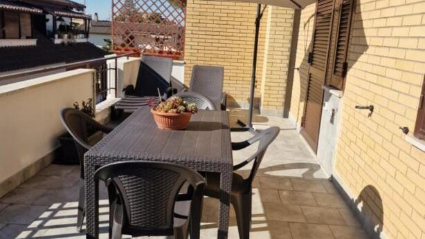 An outdoor patio with a table, chairs, and a large umbrella. - Greta family house: Luke (Roma)