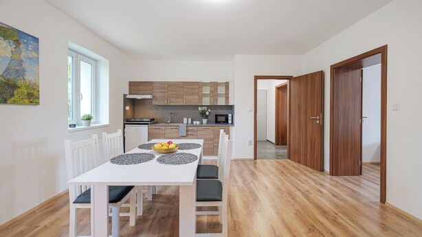 Una cocina moderna con armarios de madera, una mesa de comedor con sillas y una ventana con una planta.