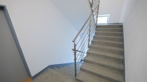 Una escalera con barandilla metálica y vista al cielo a través de un ventanal.