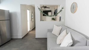 Una cocina moderna con un refrigerador empotrado, un sofá gris con cojines blancos y un reloj montado en la pared.