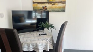 Un coin repas comprenant une table, des chaises, un téléviseur et un tableau accroché au mur.