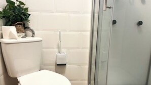 Une salle de bain moderne avec des toilettes, une douche à parois de verre et un mur recouvert de carreaux blancs.