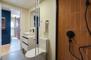 A modern bathroom with a toilet, sink, and shower. - Puerto Alto Apartments by Olala Homes (Madrid)