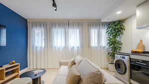 Un salon moderne avec un canapé, une table basse, un lave-linge et une plante en pot.