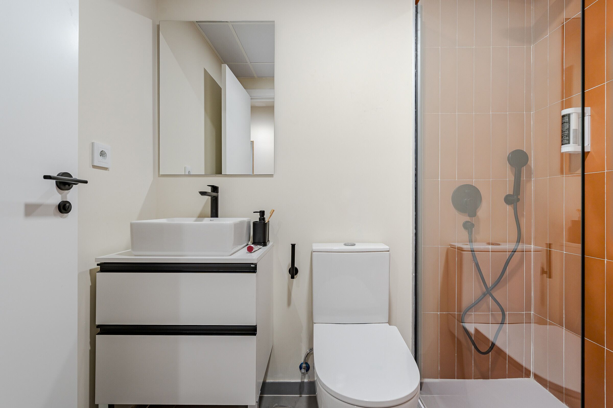 Een badkamer met een wit wastafelmeubel, toilet en douchecabine.