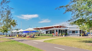 A modern building with a covered outdoor seating area, a pathway, and surrounding greenery. - Self contained studio apartment overlooking the beautiful Nightcliff foreshore with your own private balcony. (Nightcliff)