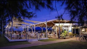 An outdoor dining area with tables and chairs, a covered seating area, and a building with a bar. - Self contained studio apartment overlooking the beautiful Nightcliff foreshore with your own private balcony. (Nightcliff)