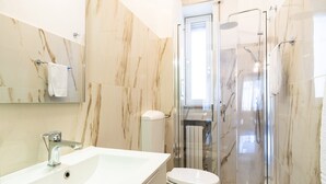 A modern bathroom with a marble sink, toilet, and glass-enclosed shower. - Appartamento Matthias by Wonderful Italy (Bari)